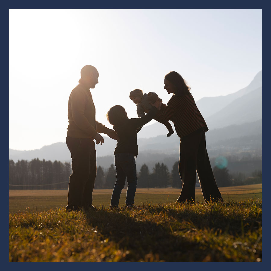 Famille recomposée en extérieur, un beau-parent marche avec deux enfants et un parent biologique, illustrant les liens affectifs dans une famille.