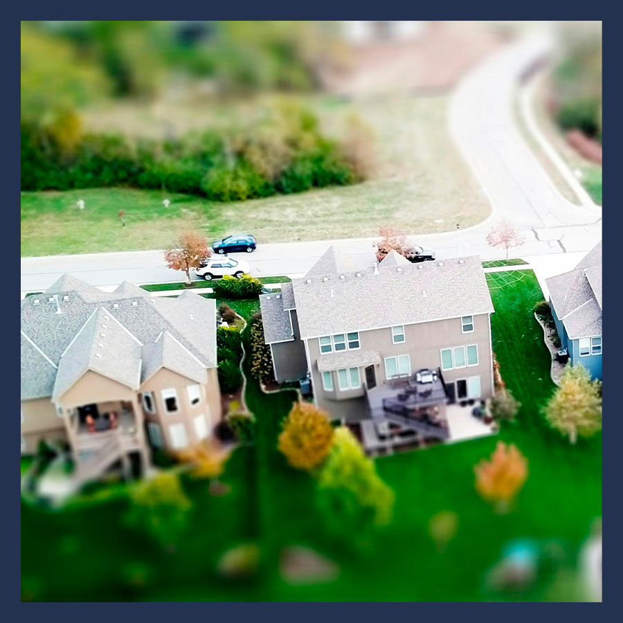 Vue aérienne d’un lotissement en copropriété horizontale avec route principale, maisons familiales et espaces verts communs