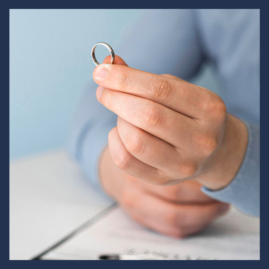 Mains d’un homme tenant une alliance au-dessus de documents officiels, illustrant la liquidation du régime matrimonial.