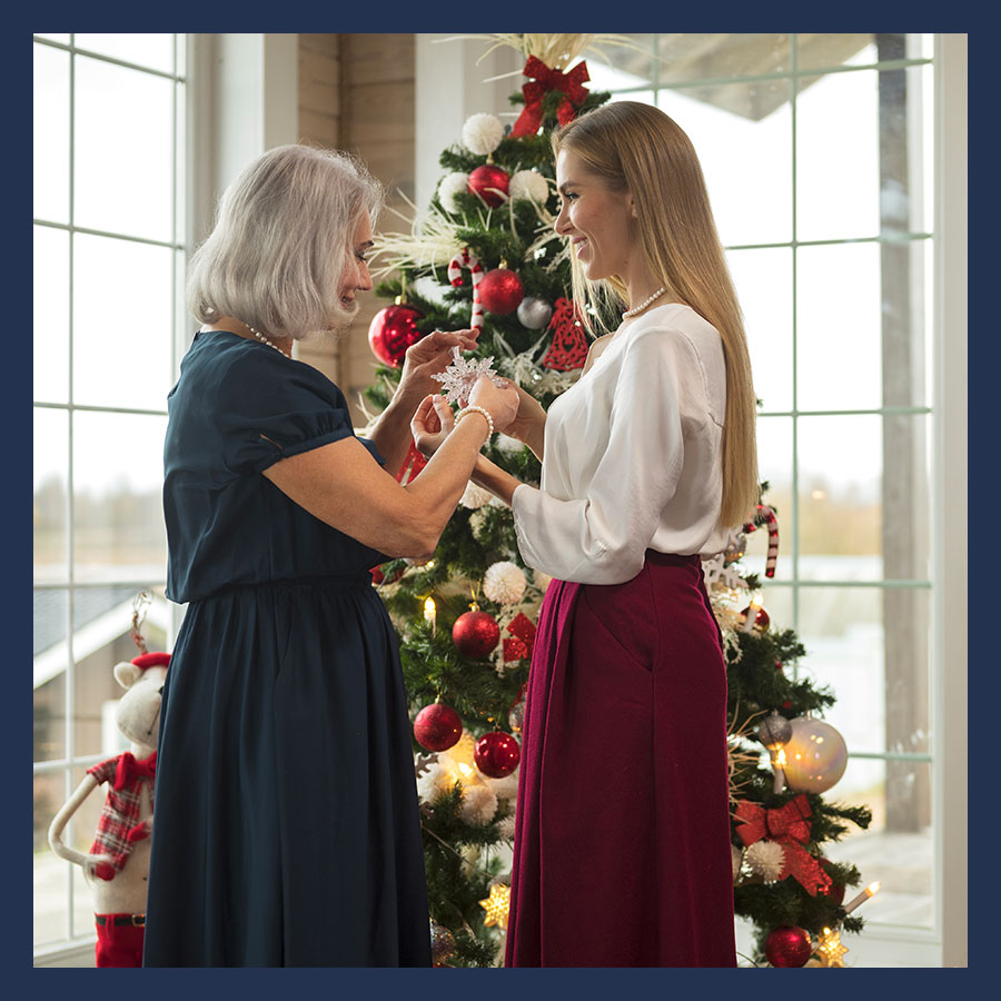Deux femmes décorant un sapin de Noël ensemble, évoquant un moment familial chaleureux.